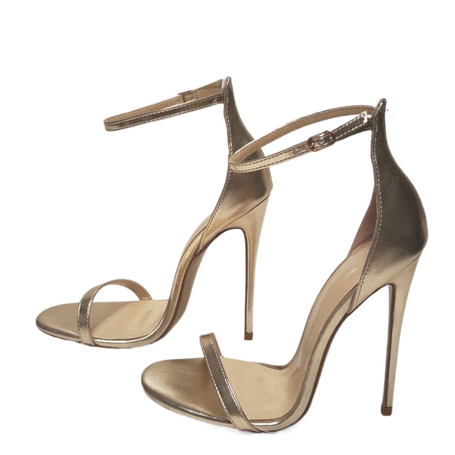 Pair of gold high-heeled sandals on a white background